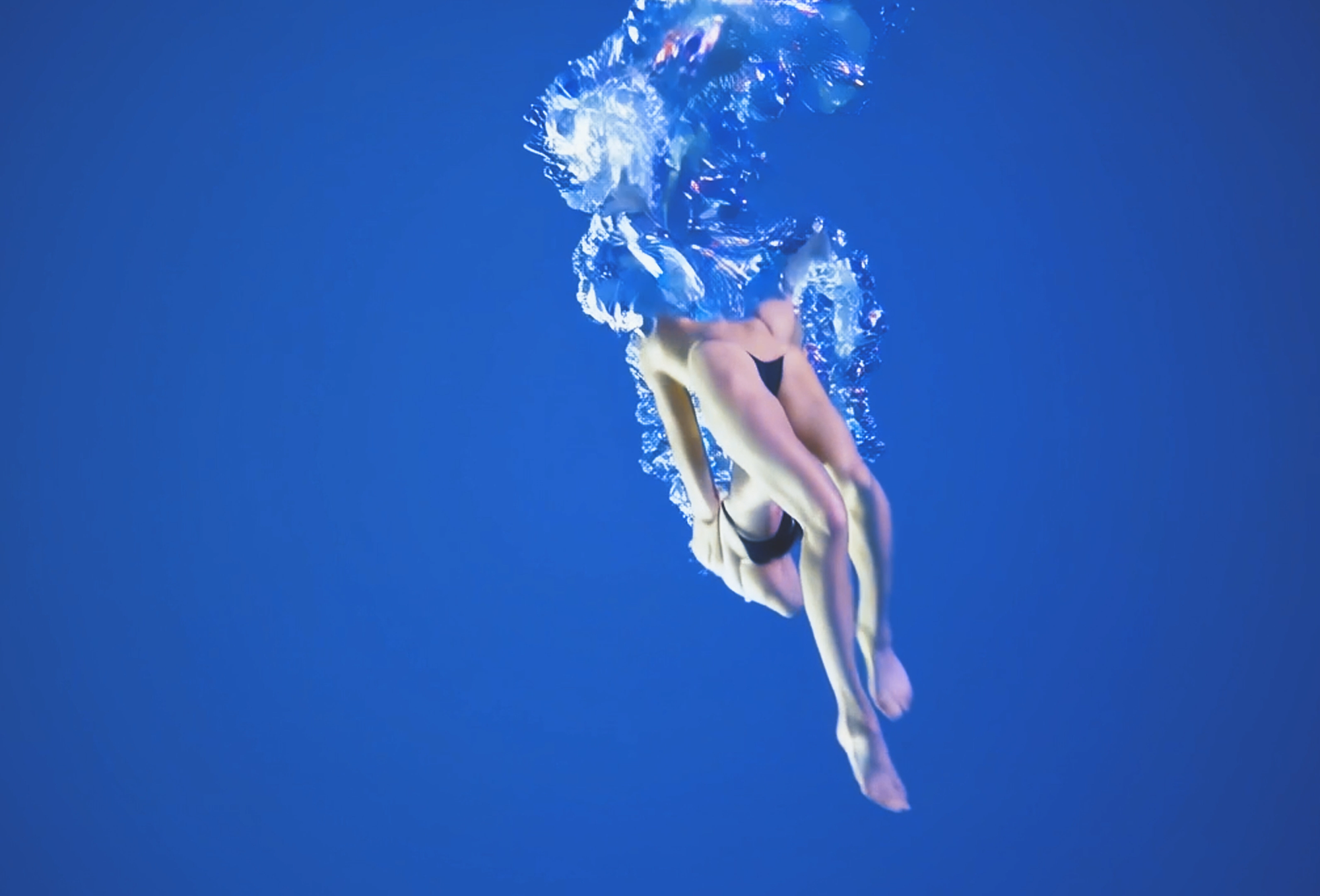 A vaguely representational shape of a woman swimming underwater surrounded by bubbles and blue.