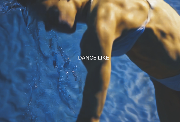 Rough shape of a woman's body against a backdrop of blue water with "Dance Like" written on the screen in all caps.