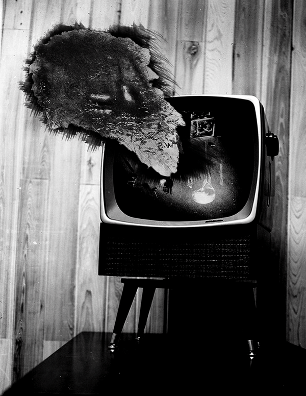 A black and white image of a television with a strange spectral smear emerging from the screen.